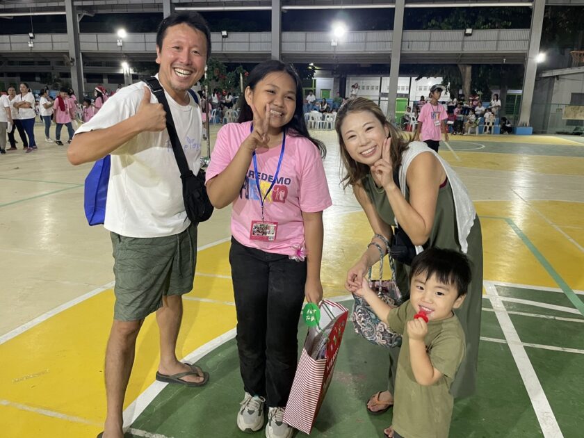 フィリピンで支援している子どもと再会した家族の写真。笑顔でピースをする子どもたちと一緒に撮影。